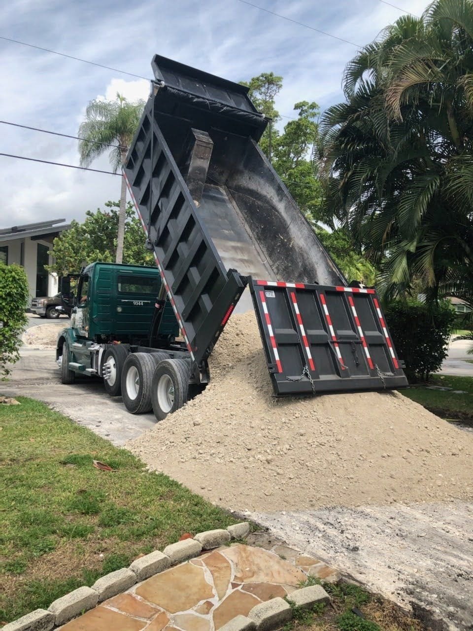 Dump truck loading base layer crushed limestone in preparation for a new asphalt driveway in Coral Springs FL