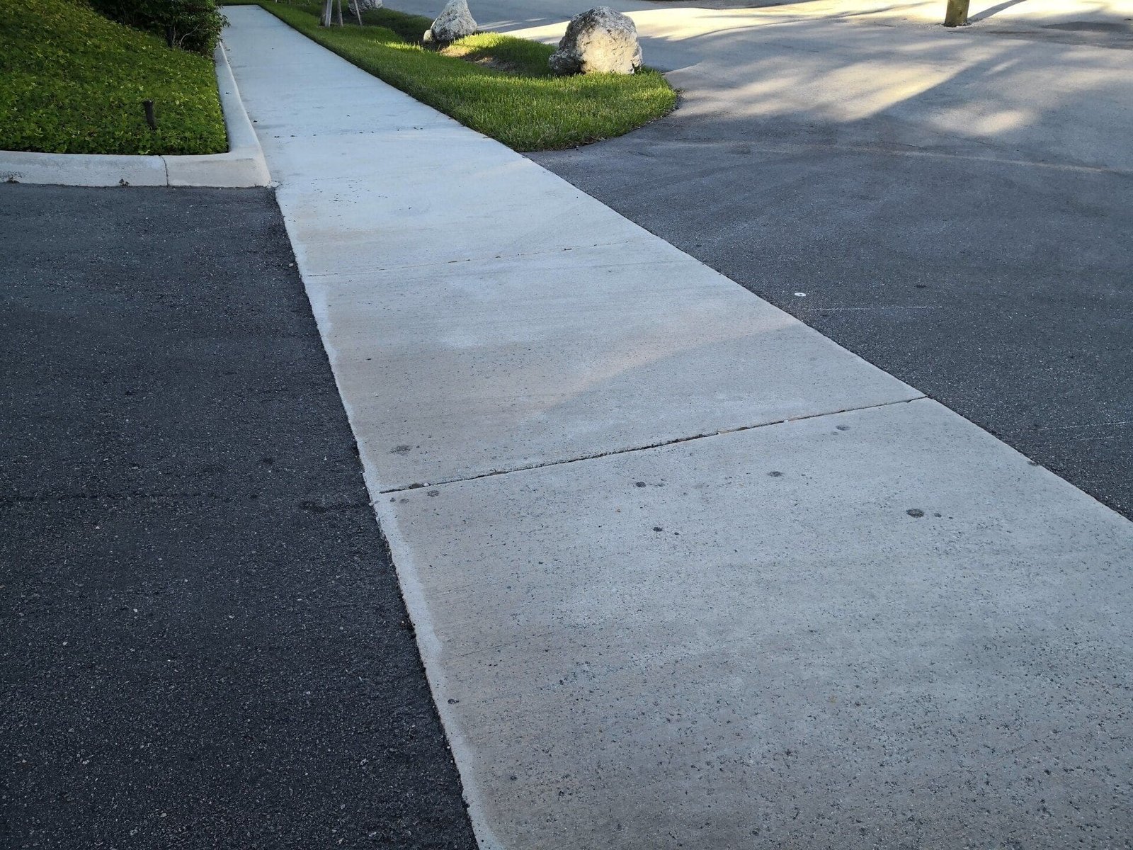 asphalt parking lot with concrete sidewalk paved in the middle. photo taken in Coral Springs, FL