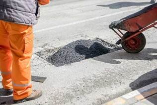 Picture of asphalt contractors patching a hole in a road